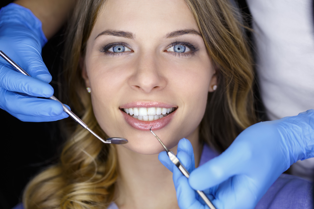 dentysta sprawdzajacy stan zebow atrakcyjnej kobiecie z pieknym usmiechem